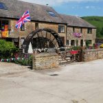 a house with a waterwheel displaying union jacks and bunting